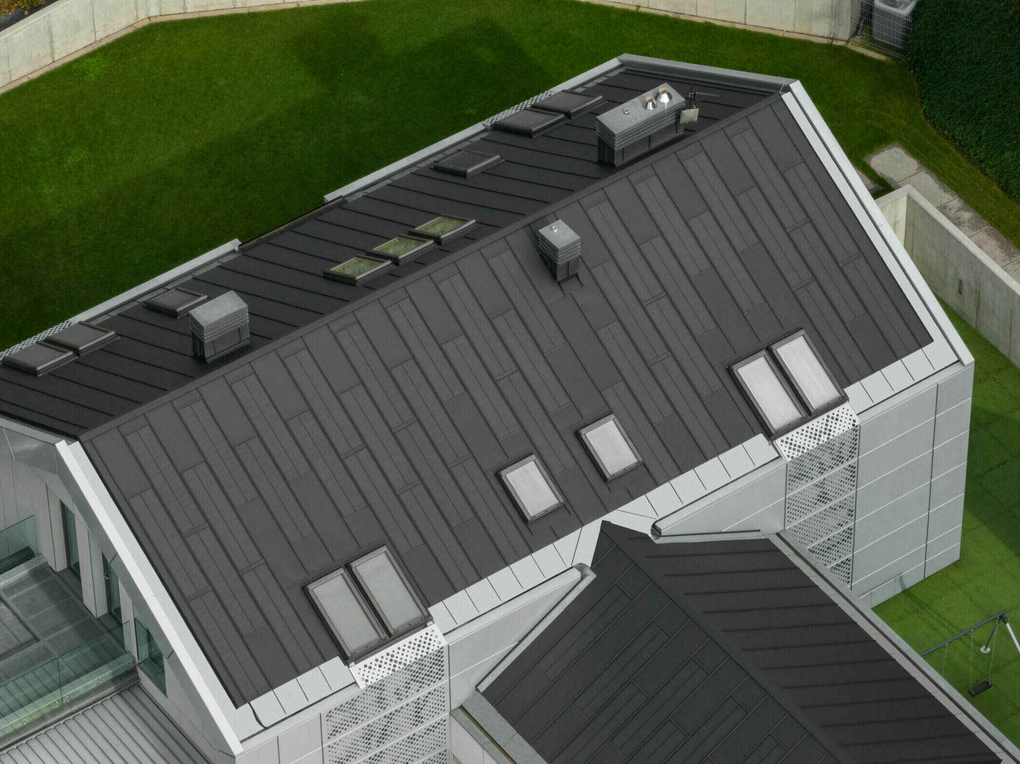Modern house with a dark SolRoof FIT VOLT standing-seam roof and skylights, seen from above; manufacturer photo of a European installation