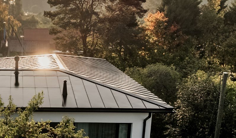 Hip-roofed house with a dark Roofit Velario standing-seam solar roof, manufacturer image